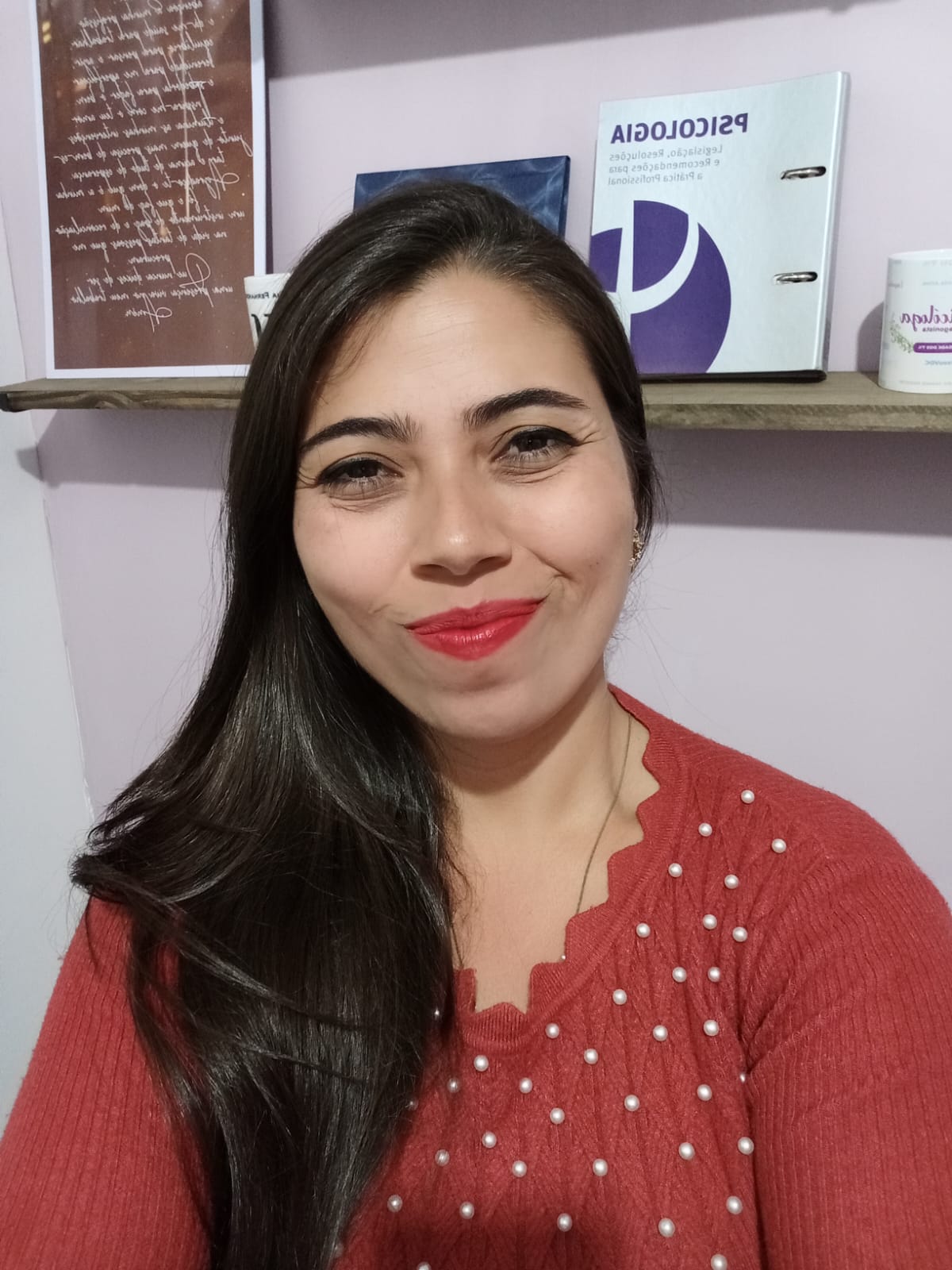 Psicóloga Luana na sala dela com fundo na prateleira